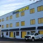 The Beehive Storage facility building with drive-up storage units with yellow doors and large utility pick-up truck parked in front
