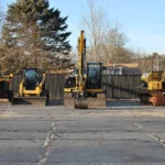 Heavy machinery that is yellow. The photo includes two backhoes, a bulldozer, and a woodchipper