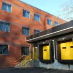 Two tractor trailer loading bays with yellow doors and a set of stairs to enter the bay with yellow railings